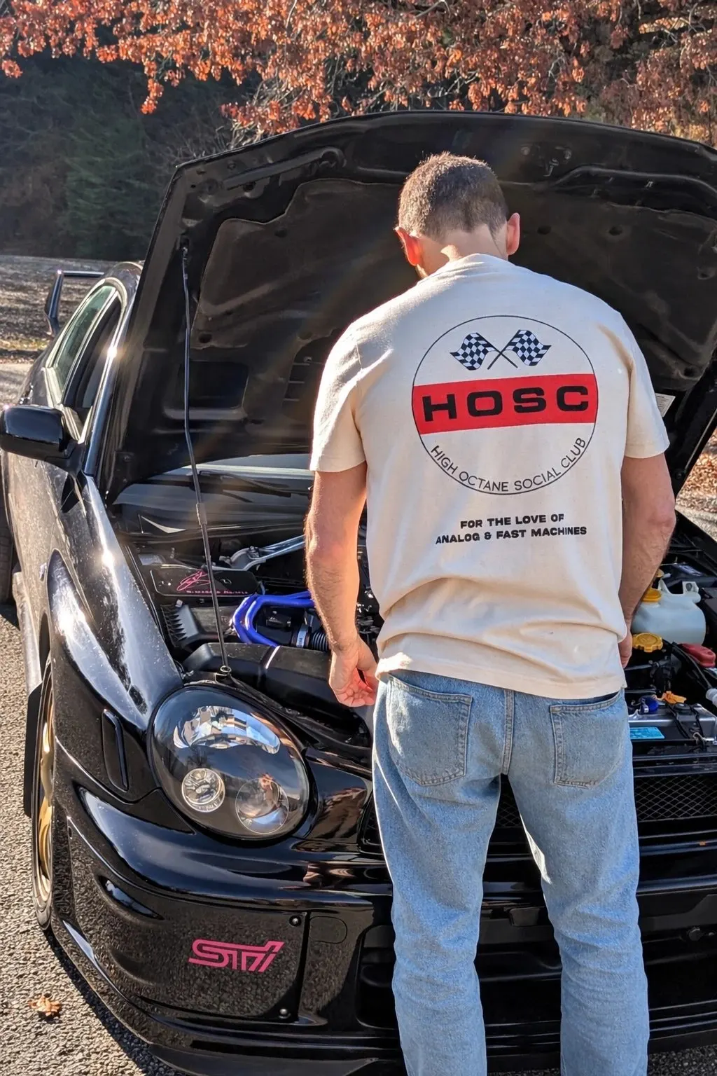 Club Badge Tee from the back, in the engine bay of a Subaru